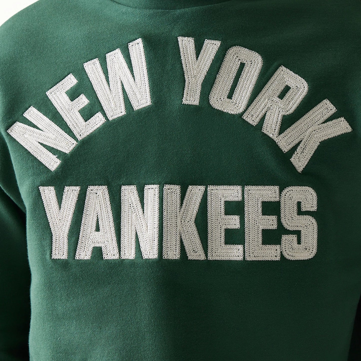 New Era New York Yankees MLB Graphic Dark Green Oversized Crew Neck Sweater, front view showing large white embroidered New York Yankees lettering in an arch on the chest against a dark green background.