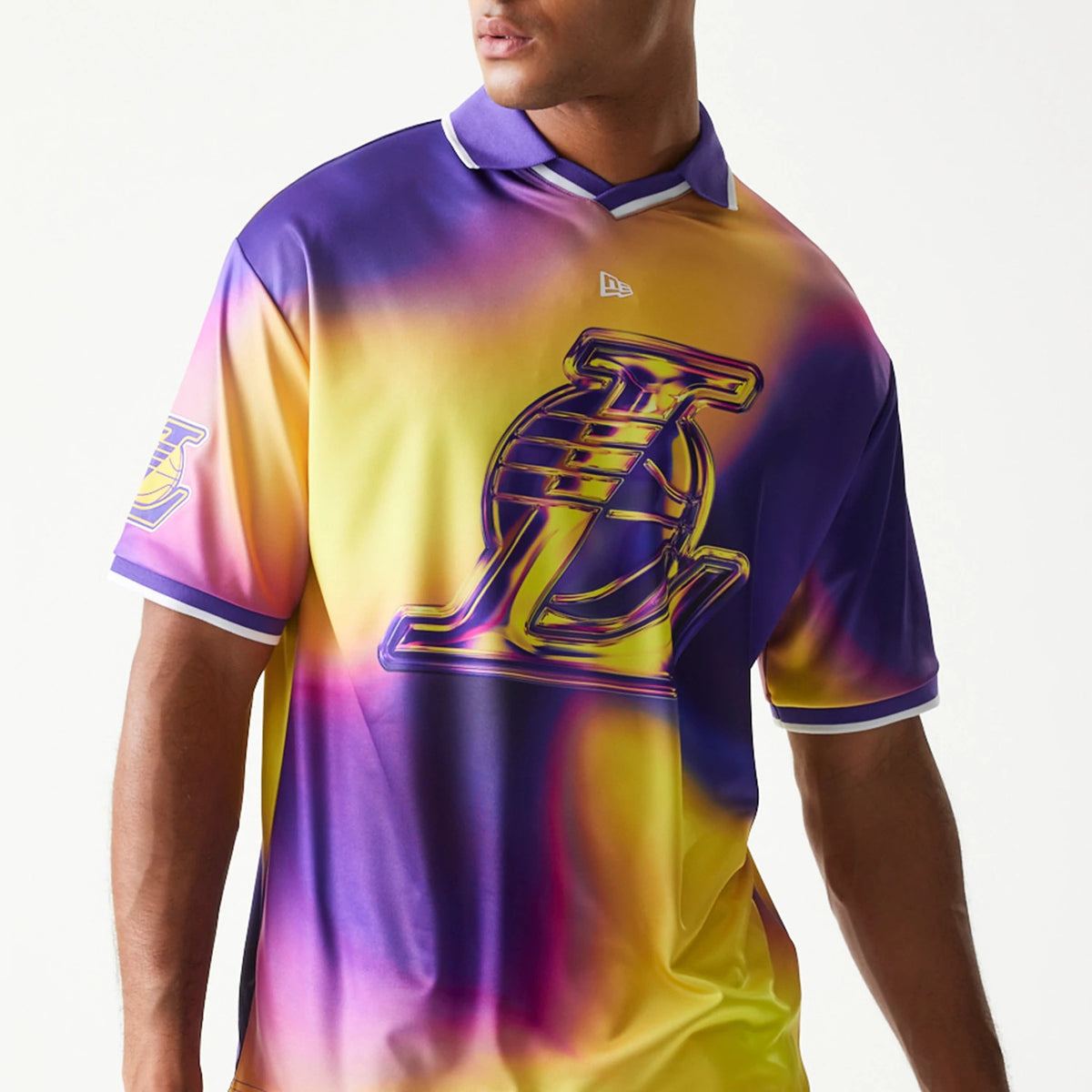 New Era LA Lakers NBA All Over Print Purple T-Shirt, front view on a model showing a vivid purple and yellow tie-dye effect with a large raised Lakers logo across the chest and an embroidered New Era logo under the collar.