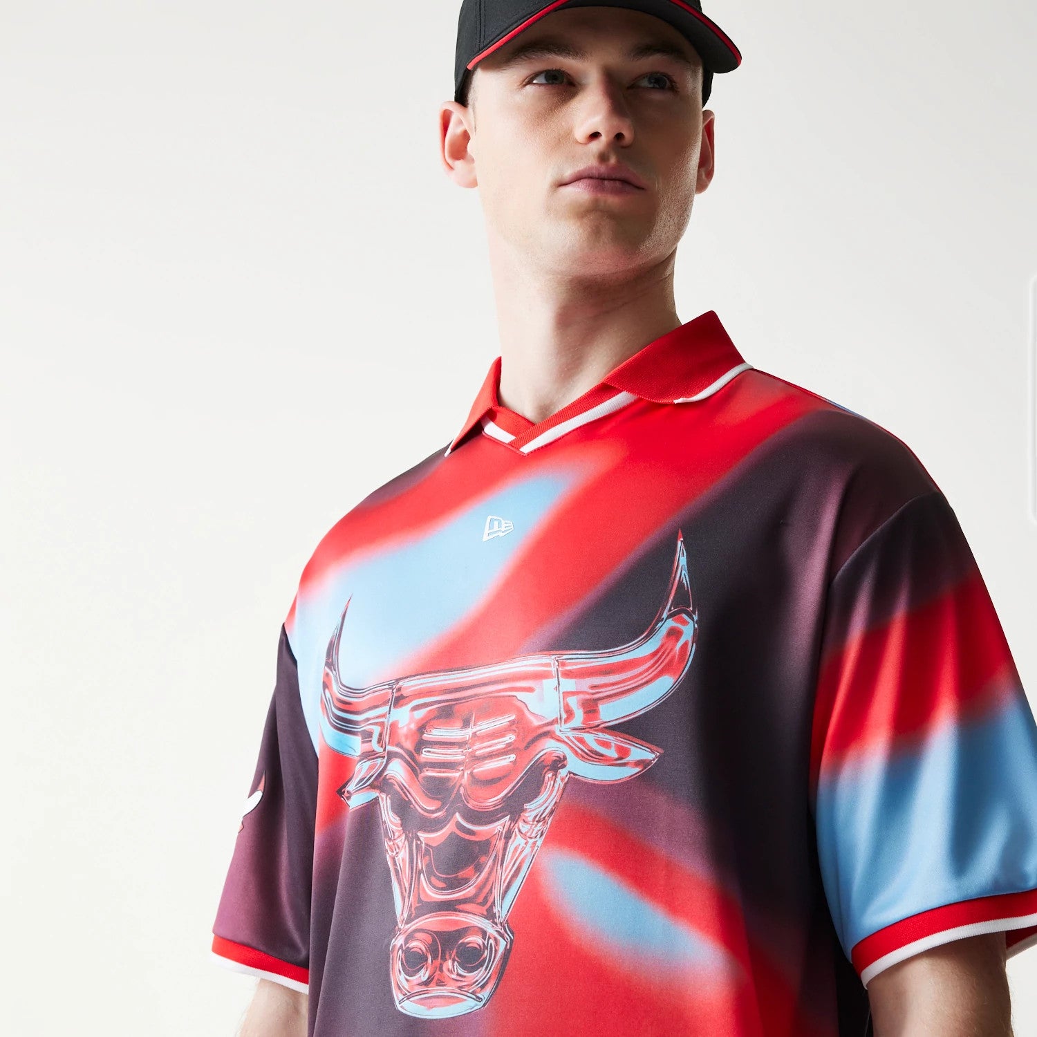 New Era Chicago Bulls NBA All Over Print Red T-Shirt, front view on-model showcasing a large graphic bull logo across the chest, red and blue swirls, and an embroidered New Era logo centred beneath the collar.