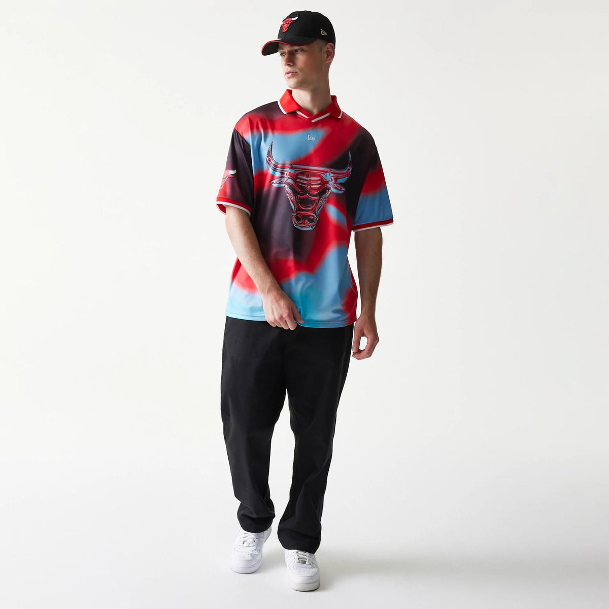 New Era Chicago Bulls NBA All Over Print Red T-Shirt, front view on-model displaying a red and blue tie-dye pattern with a large embroidered Bulls logo centred on the chest and white piping along the collar and sleeves.