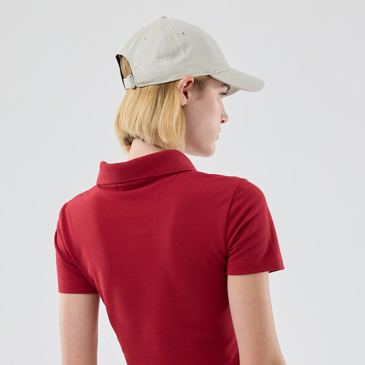 New Era New York Yankees Womens MLB Dark Red Cropped Slim Polo T-shirt, back view on a model with a beige cap, highlighting the plain design with a short collar and short sleeves, creating a casual look.