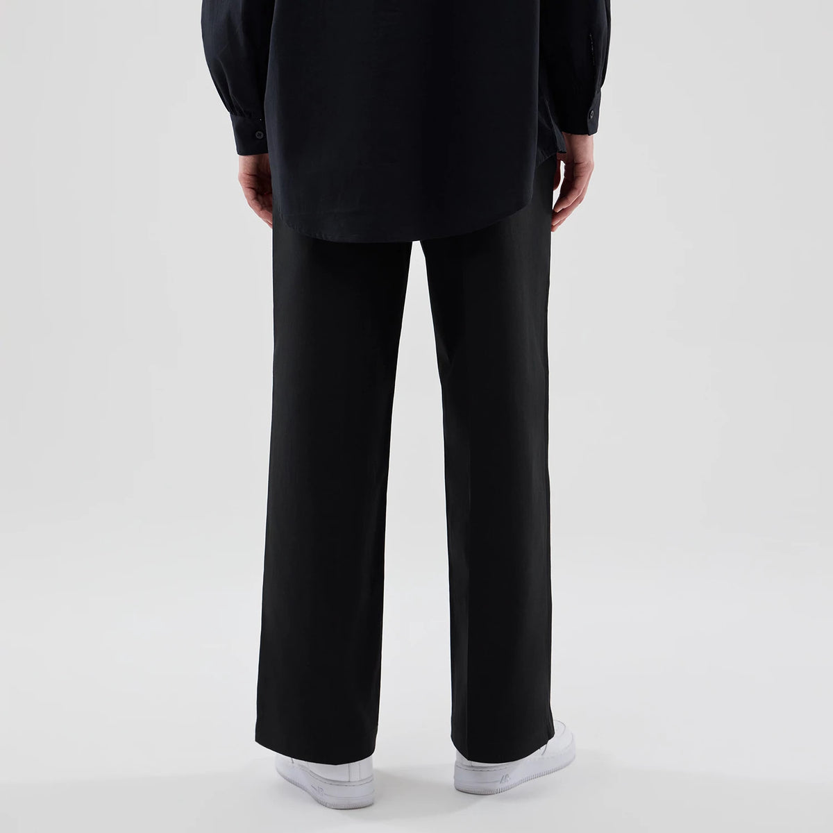 New Era New York Yankees Womens MLB Black Chino Trousers, rear view on a model wearing white trainers and a long dark shirt, showing the straight-leg cut and black fabric of the trousers.