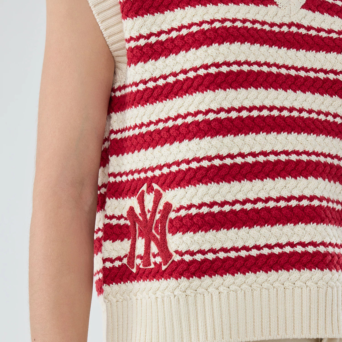 New Era New York Yankees Womens MLB Knit Stripe Dark Red Sleeveless V-neck Sweater, close-up view showing red and cream stripe pattern with an embroidered NY logo on the lower front above the ribbed hem.