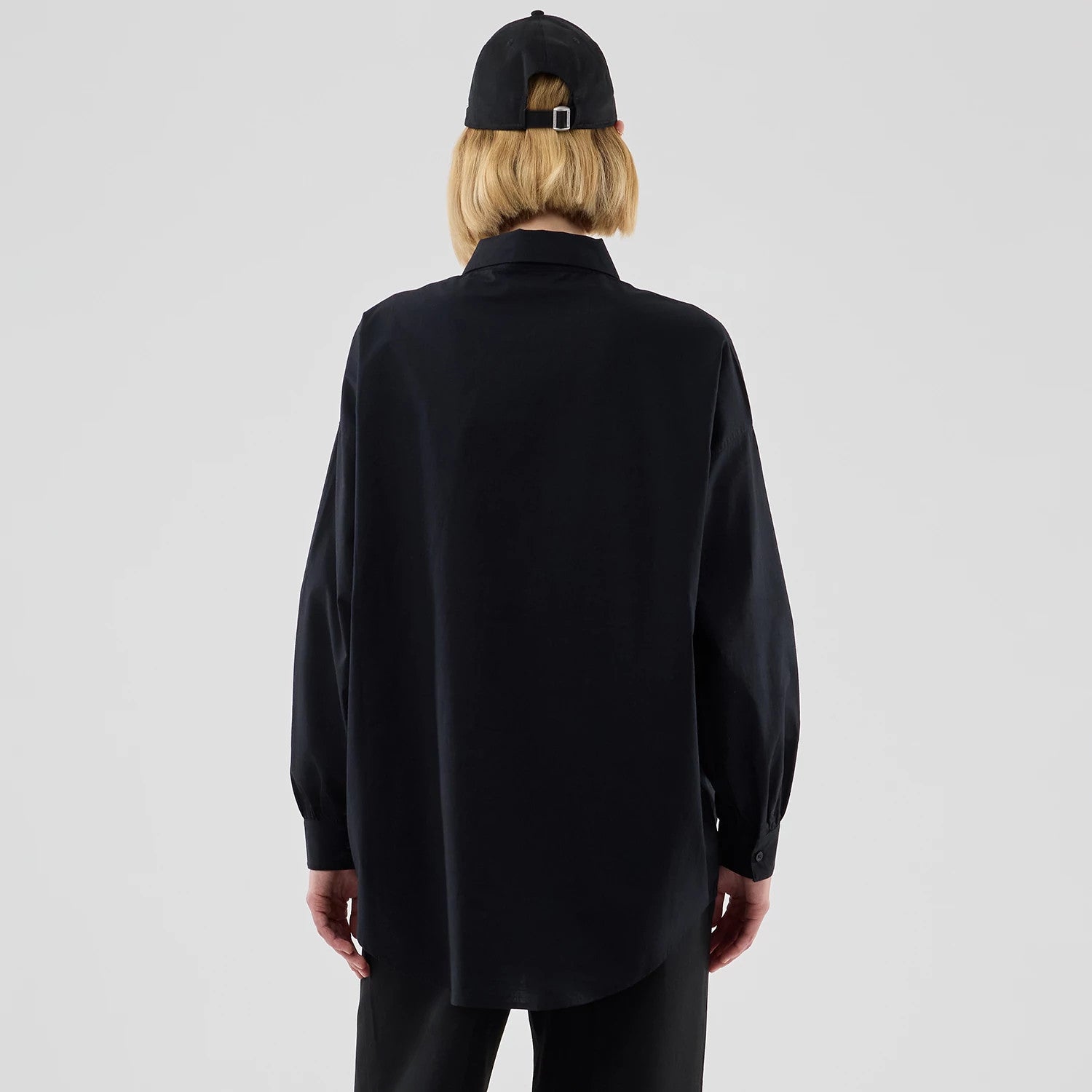 New Era New York Yankees Womens MLB Shirt Black Long Sleeve Shirt, back view on a model wearing a black cap, featuring a loose fit with a curved hem, long sleeves with buttoned cuffs, and a classic pointed collar.