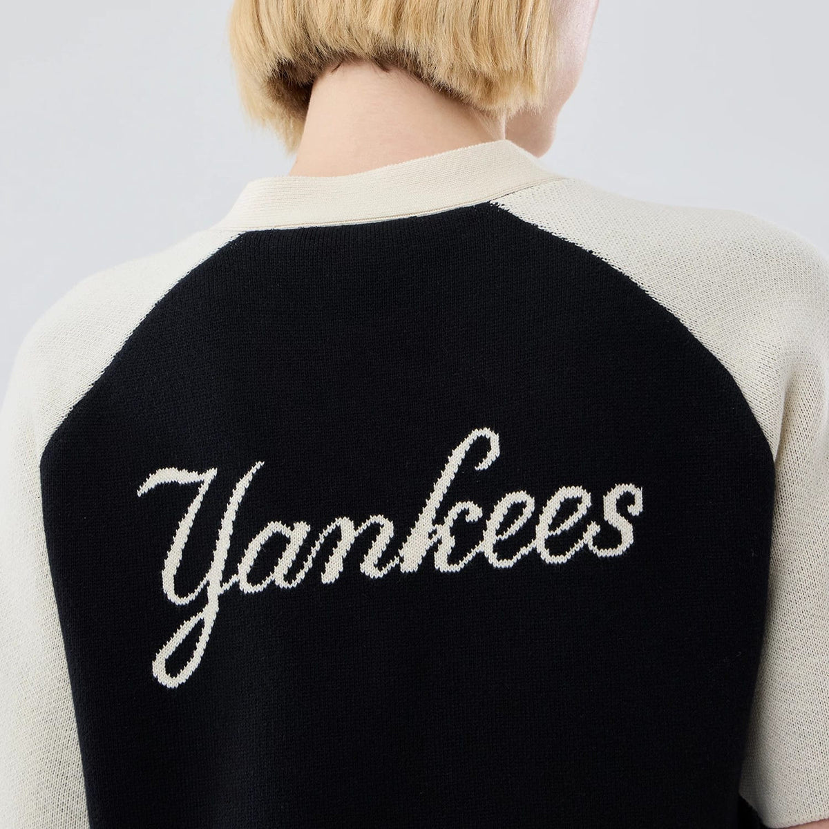 New Era New York Yankees Womens MLB Knit Stripe Black Short Sleeve Cardigan, back view on a model showing the white Yankees script logo knitted across the black panel with contrast cream sleeves.