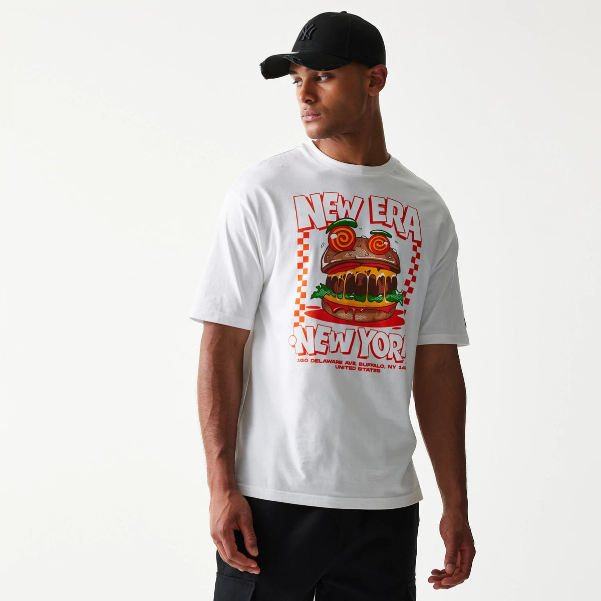 New Era Burger Food Graphic White Oversized T-Shirt, front view showing a large colourful burger graphic with New Era and New York lettering on the chest, styled with a black cap worn by the model.