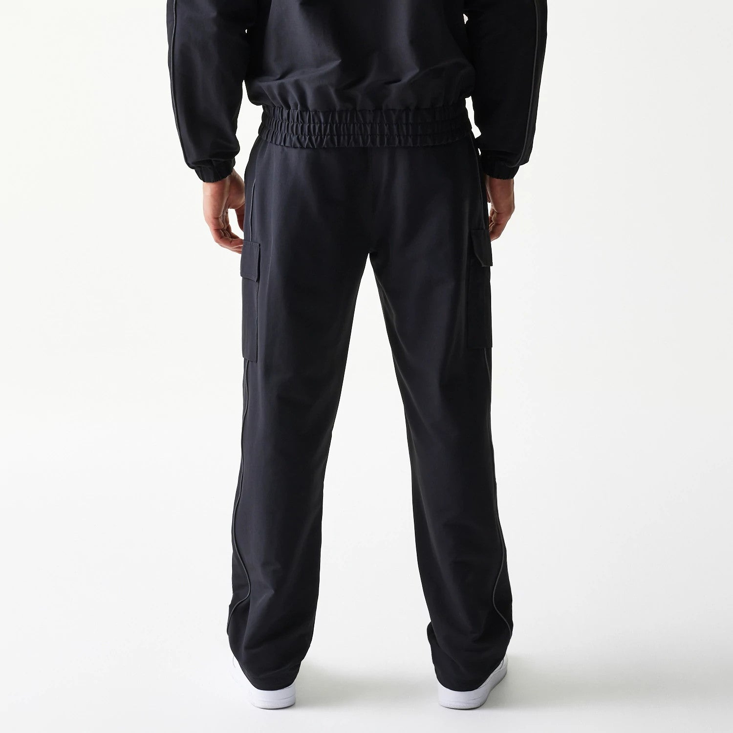 New Era New York Yankees MLB Utility Black Straight Leg Cargo Joggers, rear view on-model showing black elasticated waistband, cargo pockets on the sides, and a relaxed straight-leg fit, styled with a matching black jacket.