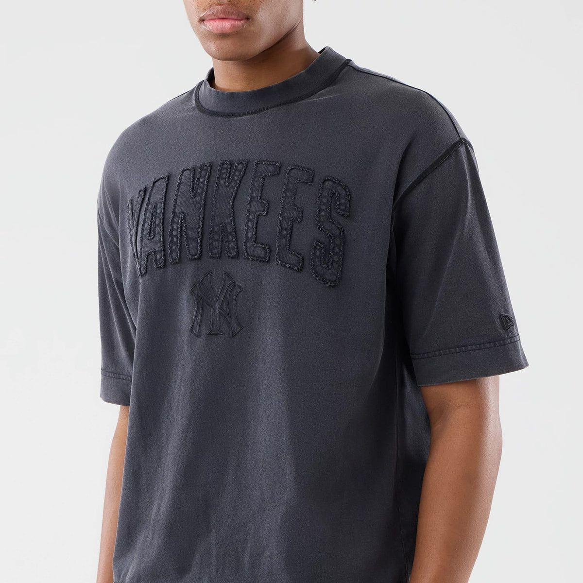 New Era New York Yankees MLB Washed Black T-Shirt, front view on-model showing the raised Yankees lettering across the chest, with an embroidered logo below and a small New Era logo on the left sleeve.