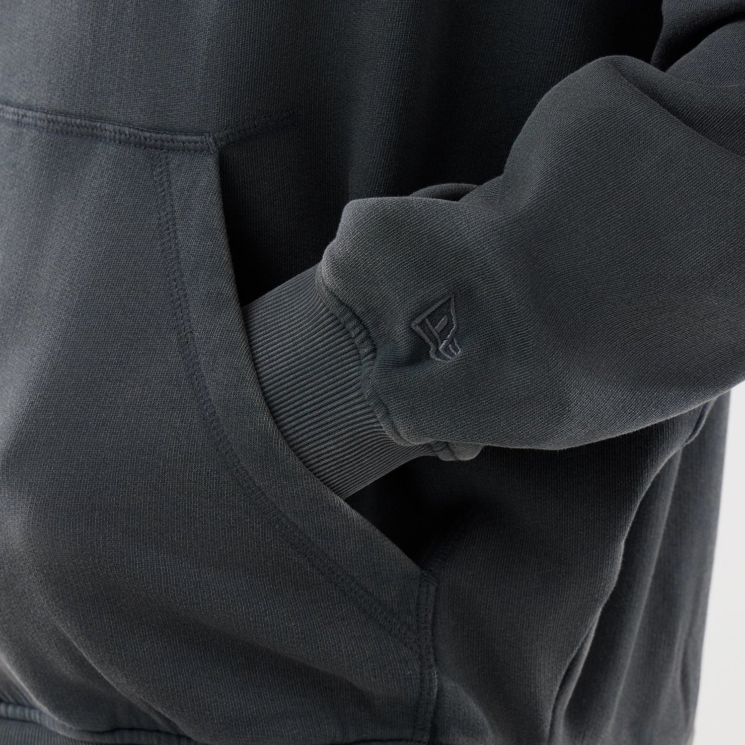 New Era LA Dodgers MLB Washed Dark Grey Full Zip Hoodie, side view showing a close-up of the kangaroo pocket and ribbed cuff with a embroidered New Era logo near the wrist on the dark grey sleeve.
