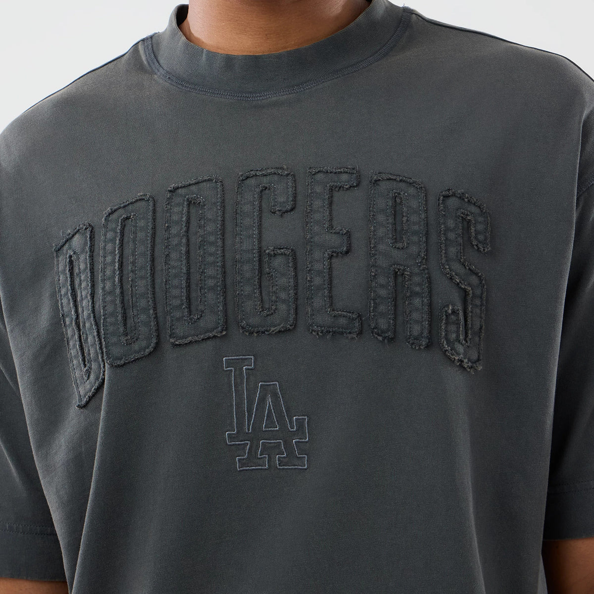 New Era LA Dodgers MLB Washed Dark Grey T-Shirt, front view displaying large DOODGERS lettering with a worn effect across the chest and embroidered LA logo positioned below, on-model styled with neckline and shoulders.