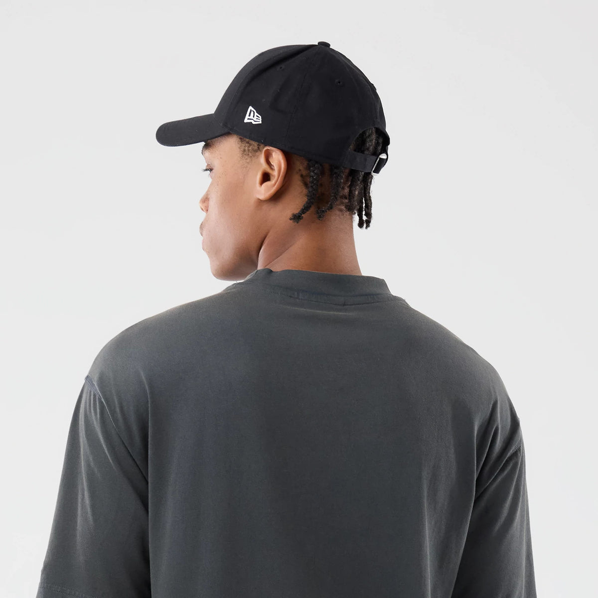 New Era LA Dodgers MLB Washed Dark Grey T-Shirt, back view on-model showing the plain dark grey fabric with short sleeves, styled with a black cap featuring a white embroidered New Era logo on the side panel.