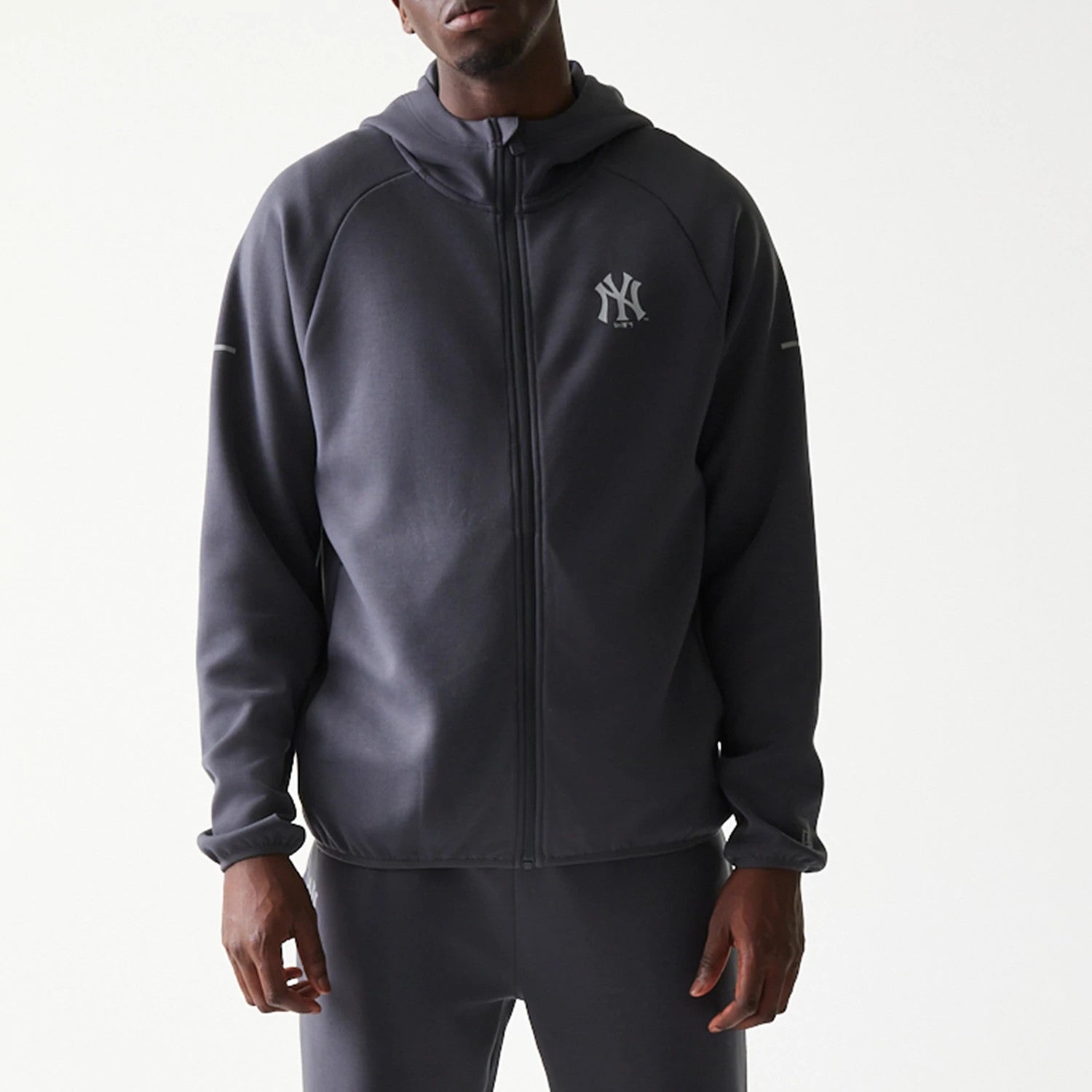 New Era New York Yankees MLB Dark Grey Full Zip Hoodie, front view on model showing the full-length zip closure, a raised Yankees logo on the left chest, and long sleeves with seam near the shoulders.