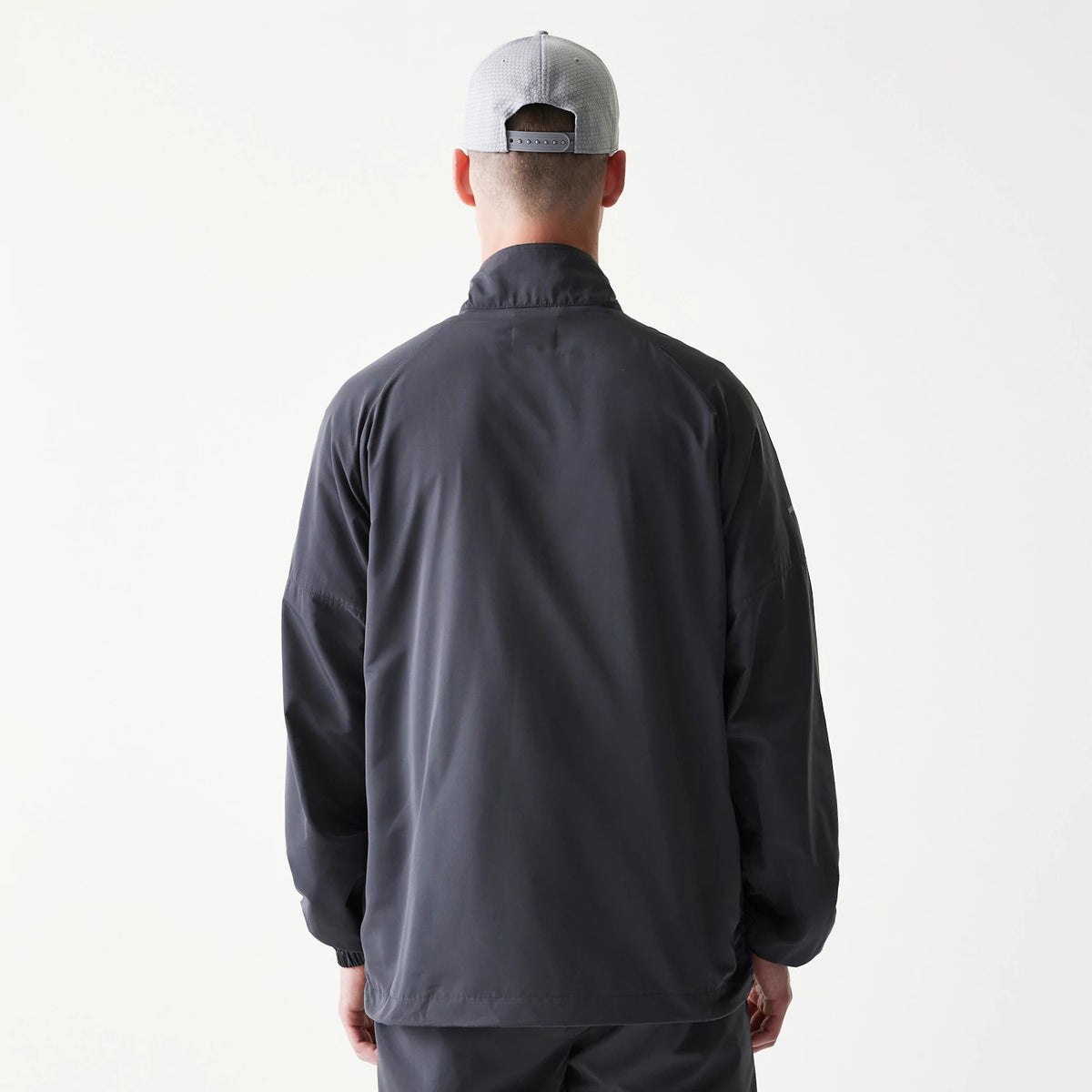 New Era New York Yankees MLB Dark Grey Jacket, back view on a model, showing a plain dark grey back with a high collar and long sleeves, paired with a light grey cap worn backwards.
