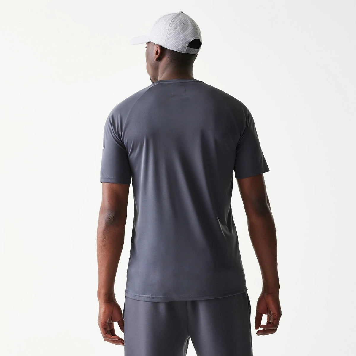 New Era New York Yankees MLB Dark Grey T-Shirt, back view on a model showing the plain dark grey fabric with short sleeves and a white embroidered New Era logo on the left sleeve, paired with matching grey shorts.