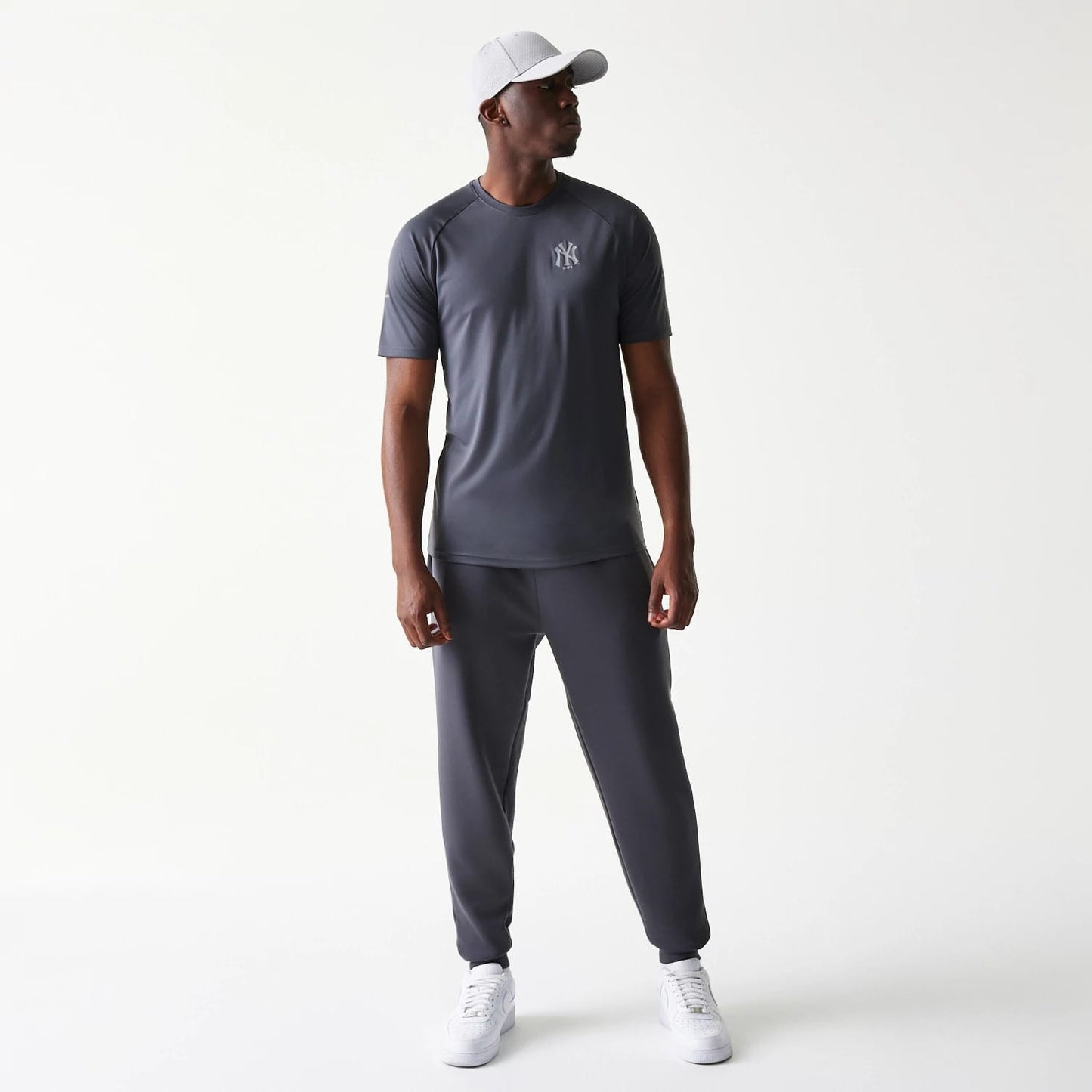 New Era New York Yankees MLB Dark Grey T-Shirt, front view on a model styled with matching dark grey trousers and white trainers, featuring an embroidered white Yankees logo on the left chest.