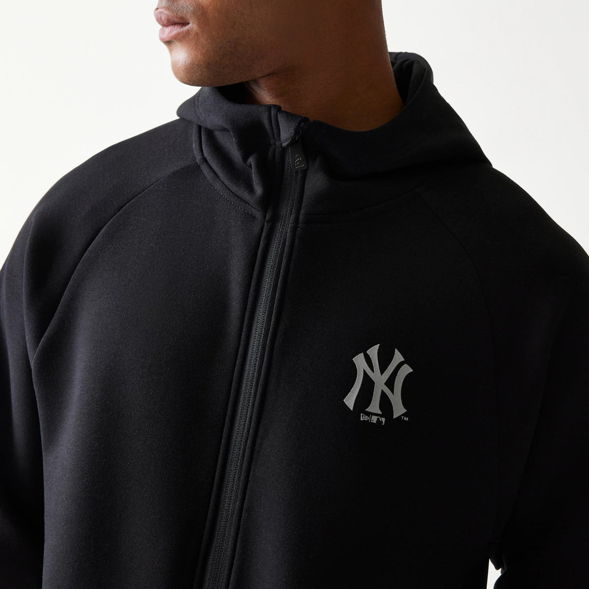 New Era New York Yankees MLB Black Full Zip Hoodie, front view showing the black hoodie with a full-length zip and a raised New York Yankees logo on the left chest, worn by a model with the hood up.