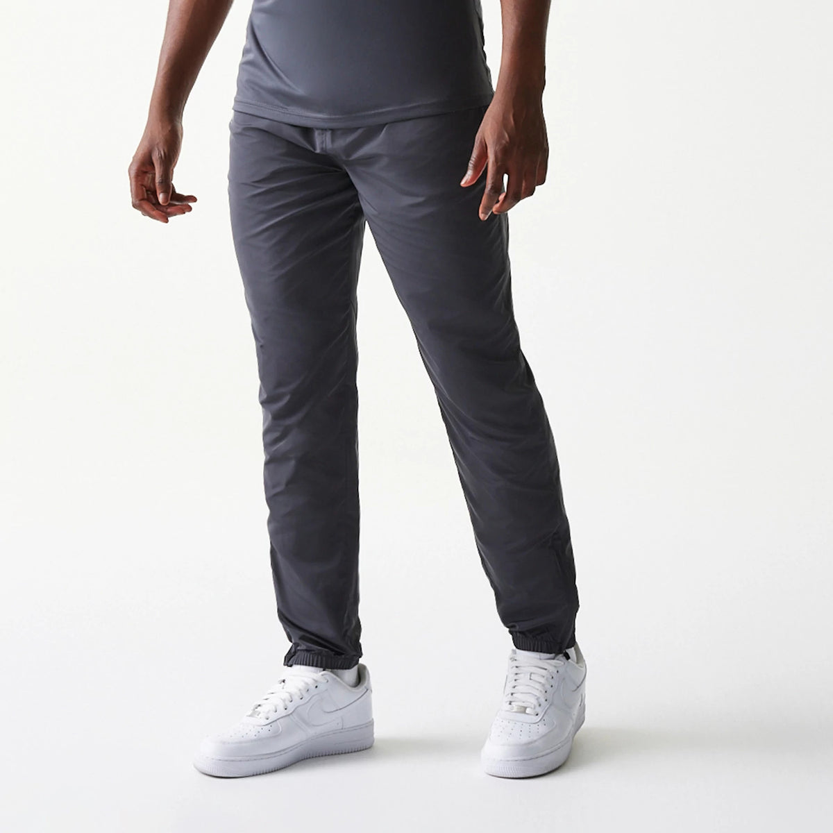 New Era New York Yankees MLB Dark Grey Track Pants, front view on a model showing the relaxed fit with elasticated cuffs and waistband, paired with white trainers for a sporty look.