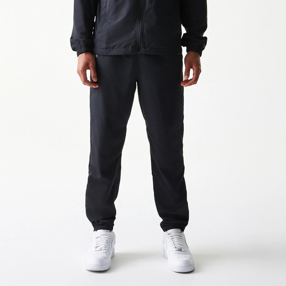 New Era New York Yankees MLB Reflective Logo Black Track Pants, front view on a model with matching jacket and white trainers, showing elasticated cuffs and a Yankees reflective logo on the left thigh.