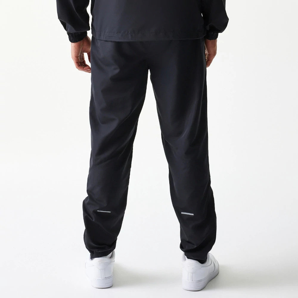 New Era New York Yankees MLB Reflective Logo Black Track Pants, rear view on a model showing reflective details near the ankles, with elasticated cuffs and a loose fit, paired with white trainers.