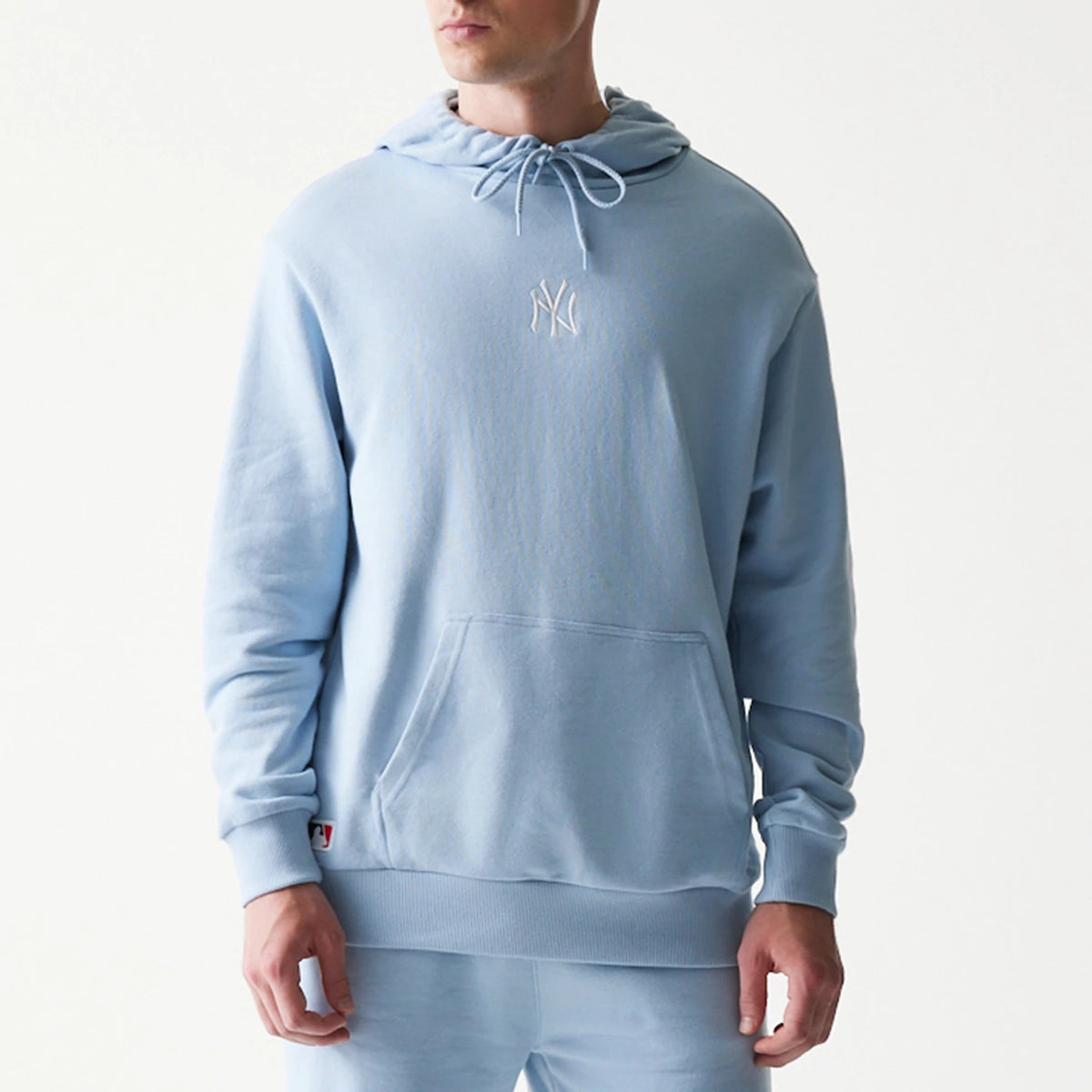 New Era New York Yankees MLB Midi Pastel Blue Oversized Pullover Hoodie, front view on a model showing a white embroidered Yankees logo on the centre chest, a drawstring hood, long sleeves, and a kangaroo pocket at the front.