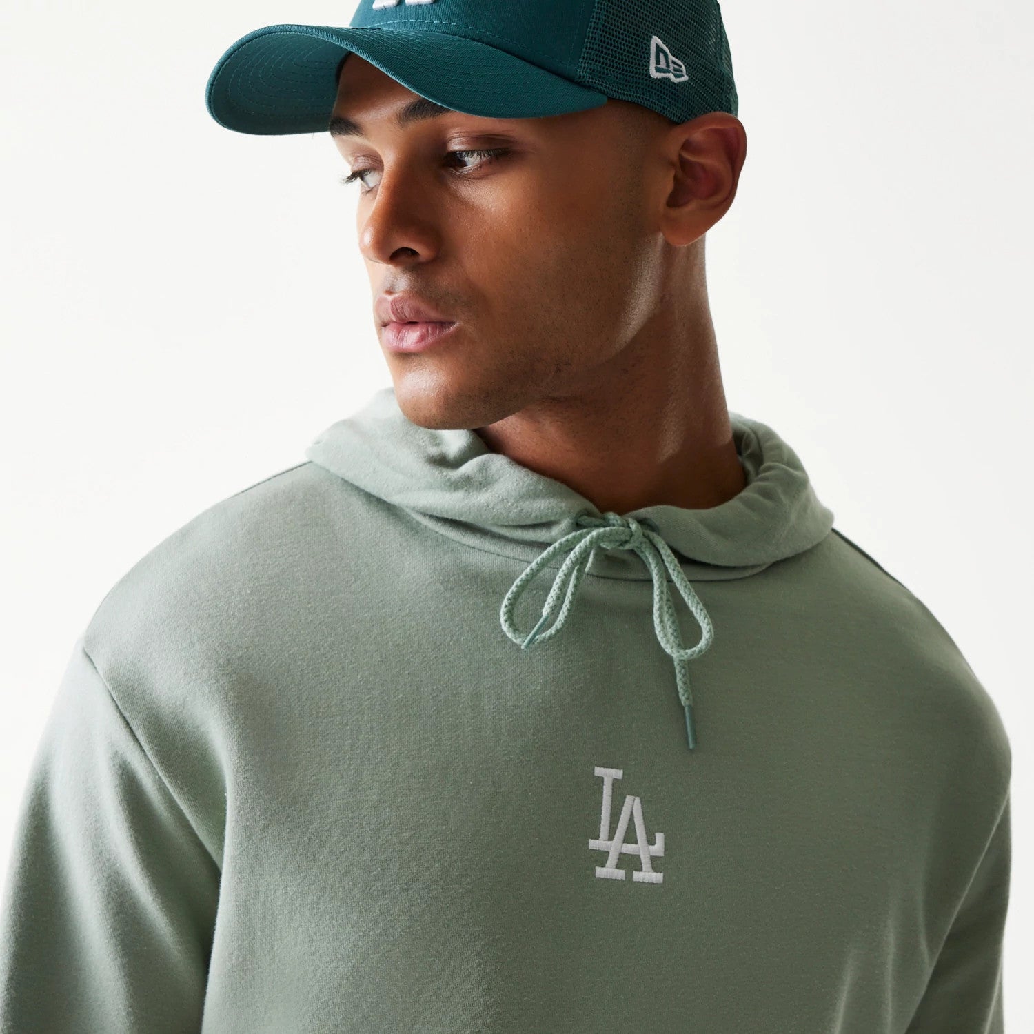 New Era LA Dodgers MLB Midi Green Oversized Pullover Hoodie, front view on a model, featuring an embroidered white LA logo on the chest with an adjustable drawstring hood and a simple, clean design.