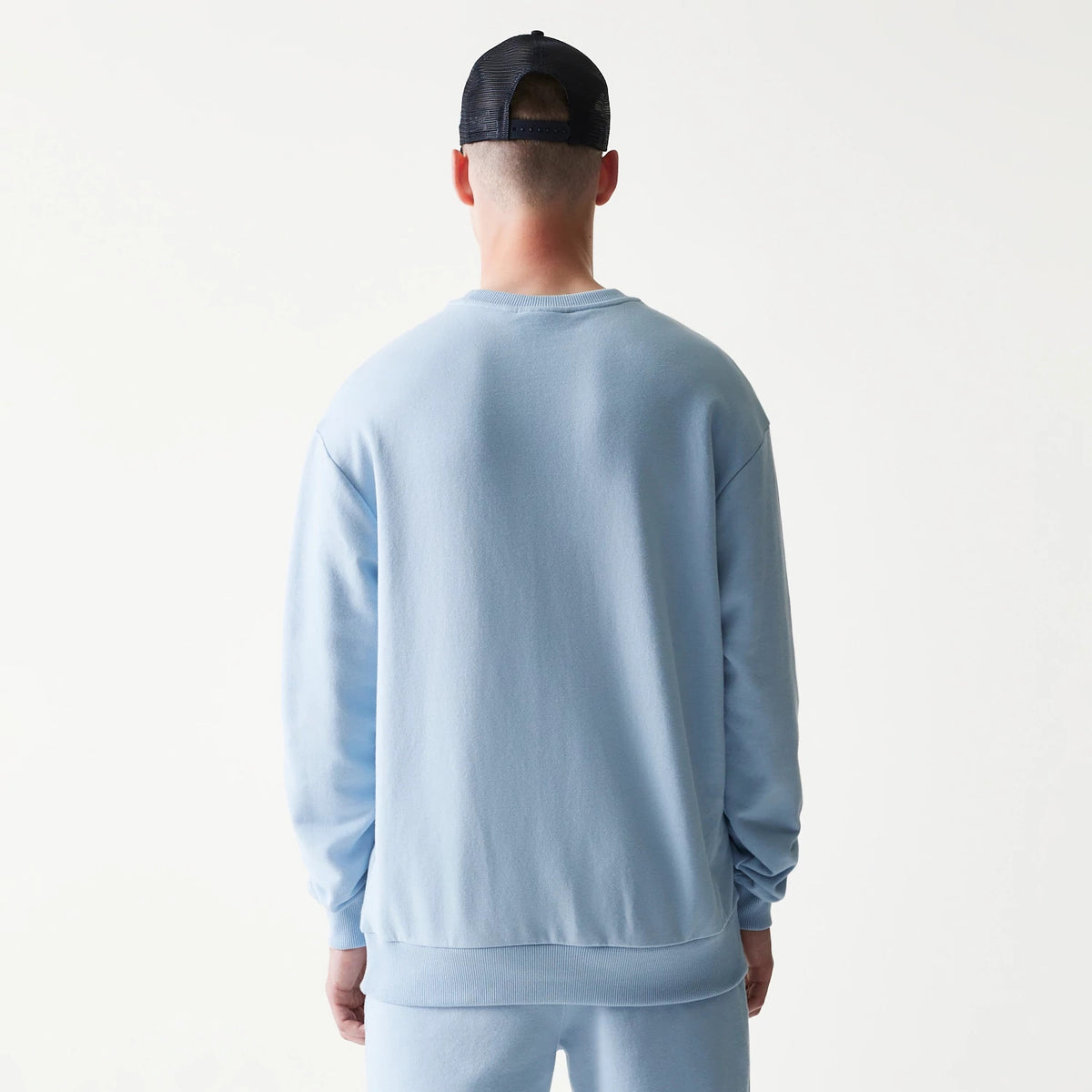 New Era New York Yankees MLB Midi Pastel Blue Oversized Crew Neck Sweater, back view on a model showing the relaxed fit and ribbed hem and cuffs of the pastel blue fabric with a plain design.