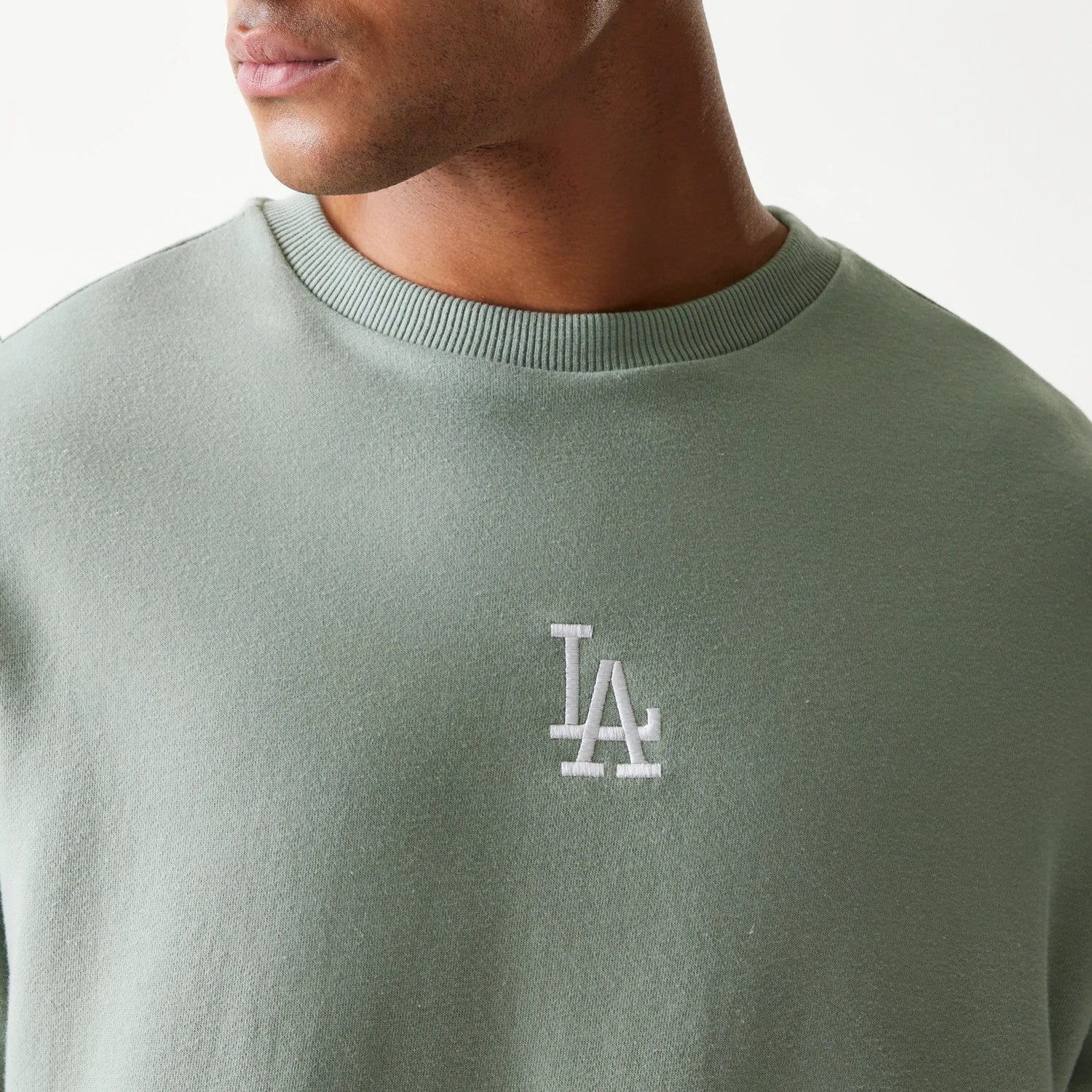 New Era LA Dodgers MLB Midi Green Oversized Crew Neck Sweater, front view on a model showing the white embroidered LA logo centred on the chest, with a ribbed crew neck and a green fabric.
