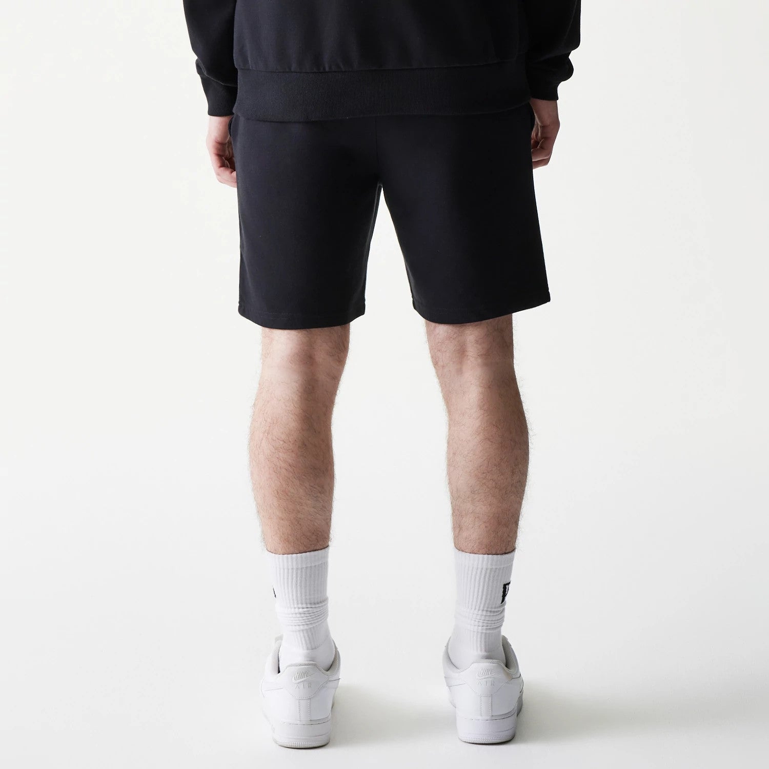 New Era Chicago Bulls NBA Core Black Shorts, back view showing the plain black design with a straight hemline, worn by a model standing, highlighting the simplicity and casual style of the shorts.