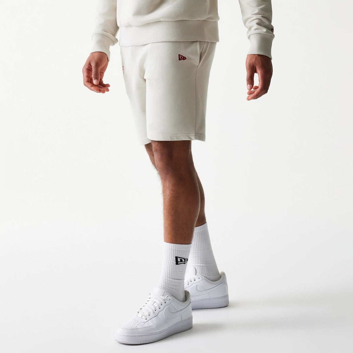 New Era LA Lakers NBA League Essential Light Beige Shorts, on-model front view showing a light beige colour with an embroidered New Era logo on the left leg, paired with matching white socks and trainers for a look.