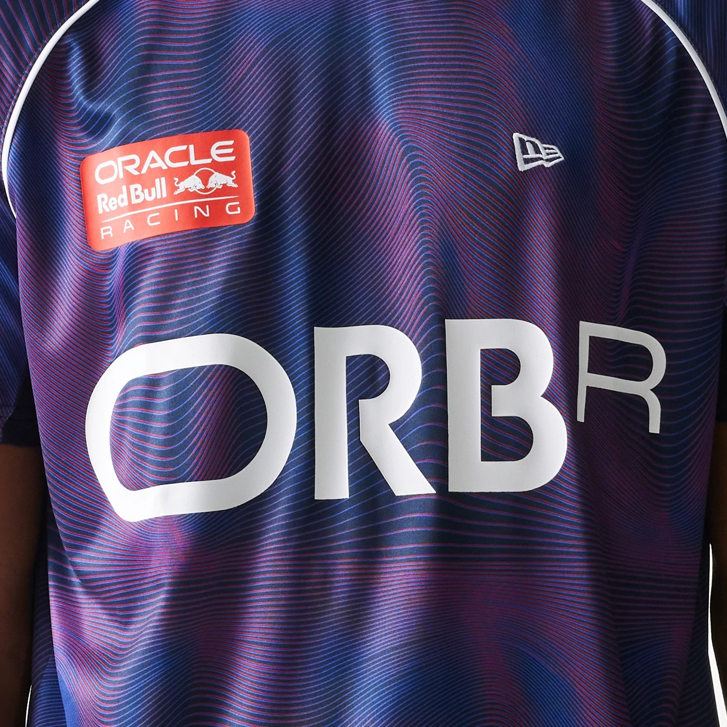 New Era Red Bull Racing All Over Print Dark Blue Football T-Shirt, front view displaying a pattern with a white printed ORBR logo across the chest, a red Oracle Red Bull Racing logo on the left side.