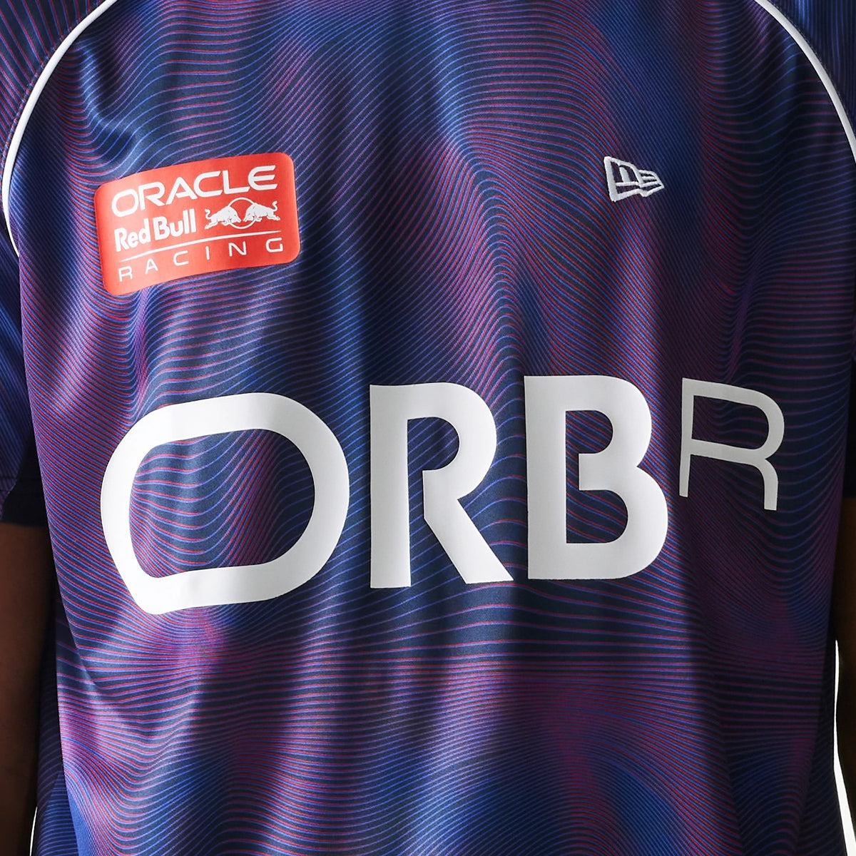 New Era Red Bull Racing All Over Print Dark Blue Football T-Shirt, front view displaying a pattern with a white printed ORBR logo across the chest, a red Oracle Red Bull Racing logo on the left side.
