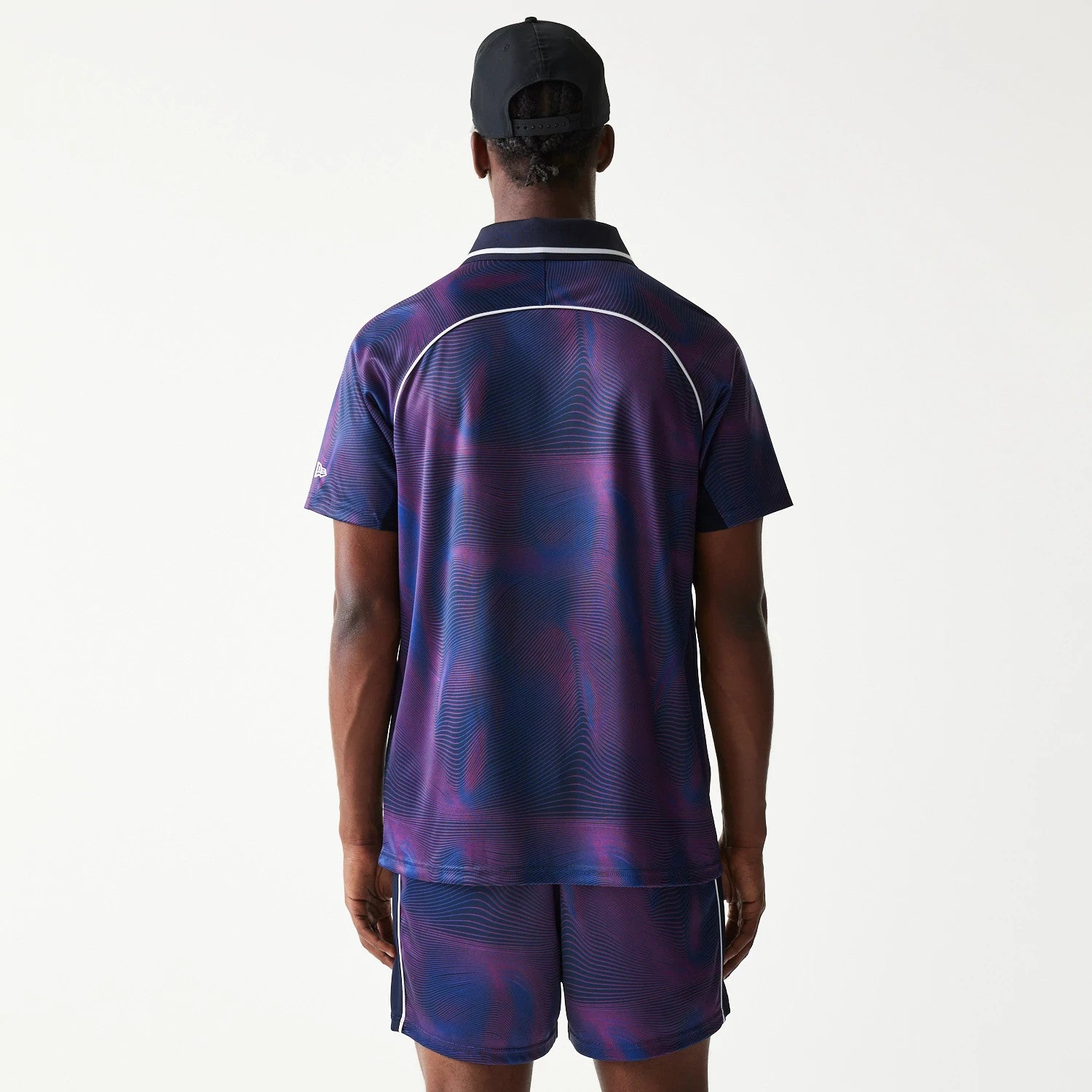 New Era Red Bull Racing All Over Print Dark Blue Football T-Shirt, back view on a model showing the dark blue and purple pattern with light piping detail across the shoulders and sleeves, paired with matching shorts.