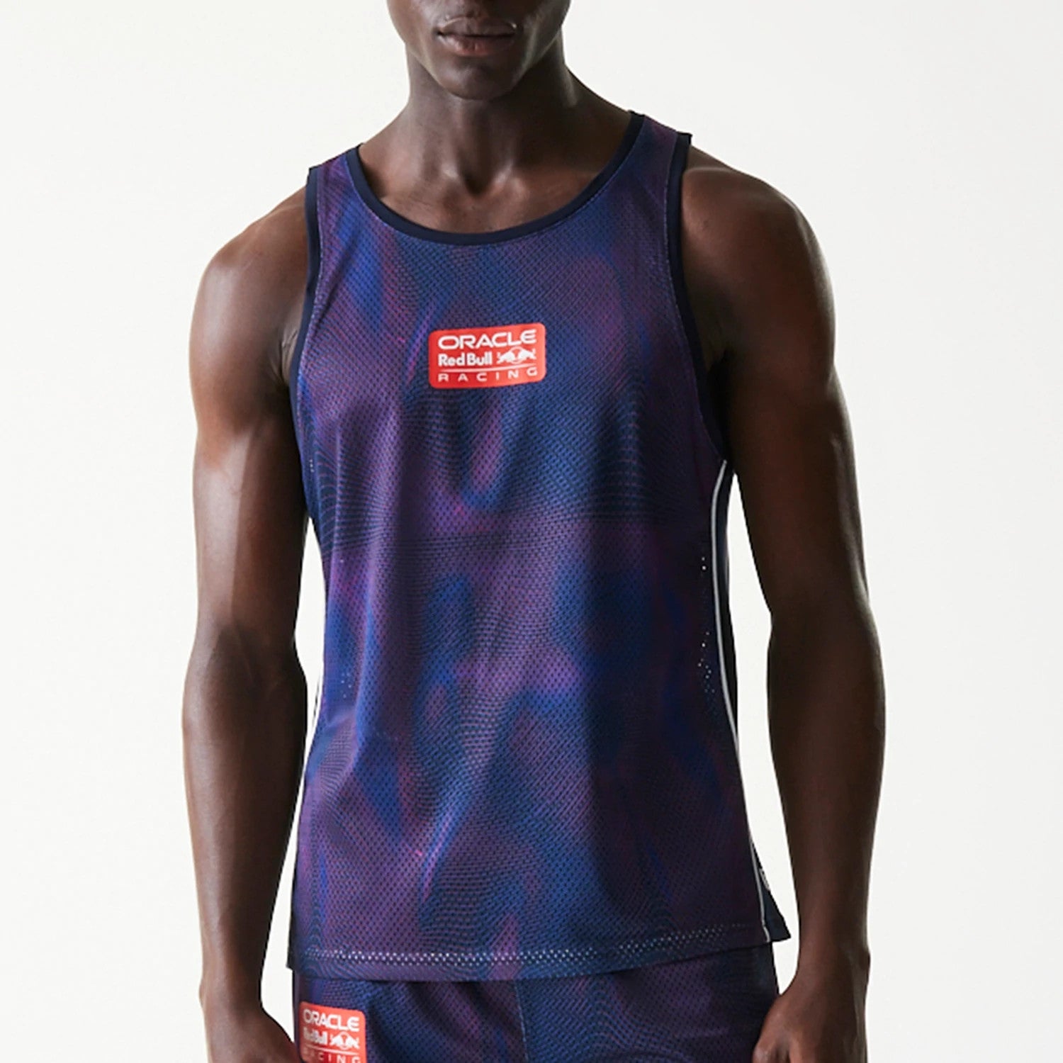New Era Red Bull Racing Dark Blue Mesh Tank Top, front view on a model with the Oracle Red Bull Racing logo in red and white on the chest, featuring a dark blue mesh fabric with a textured pattern.