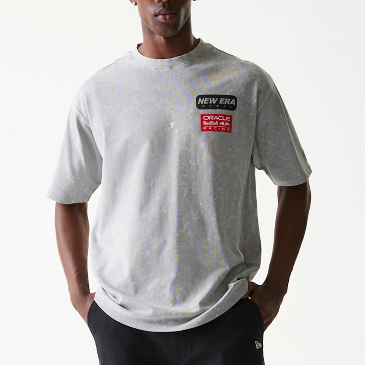 New Era Red Bull Racing Linear Graphic Grey Oversized T-Shirt, front view on a model showing New Era and Oracle Red Bull Racing patches on the left chest against a speckled grey fabric with relaxed sleeves.