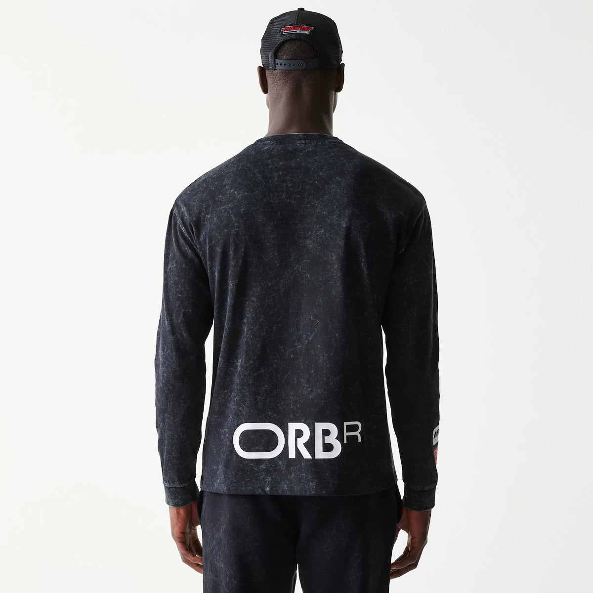 New Era Red Bull Racing Linear Graphic Black Long Sleeve T-Shirt, back view on a model wearing a cap, featuring white ORBR lettering across the lower back and a printed Red Bull Racing graphic on the right sleeve.