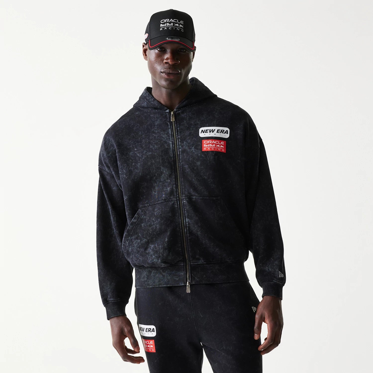 New Era Red Bull Racing Dropped Shoulder Black Dropped Shoulder Full Zip Hoodie, front view on-model displaying a zip closure, an embroidered New Era logo on the upper right chest, and Oracle Red Bull Racing patches on the left chest.