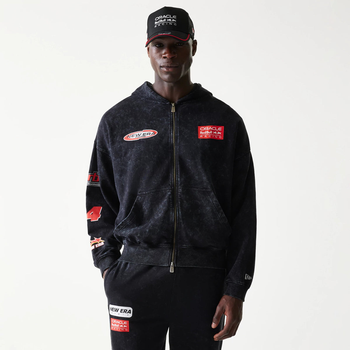 New Era Red Bull Racing Graphic Black Dropped Shoulder Full Zip Hoodie, front view on-model showing multiple patches including Oracle Red Bull Racing on the chest, New Era on the opposite side, and number 4 on the sleeve.