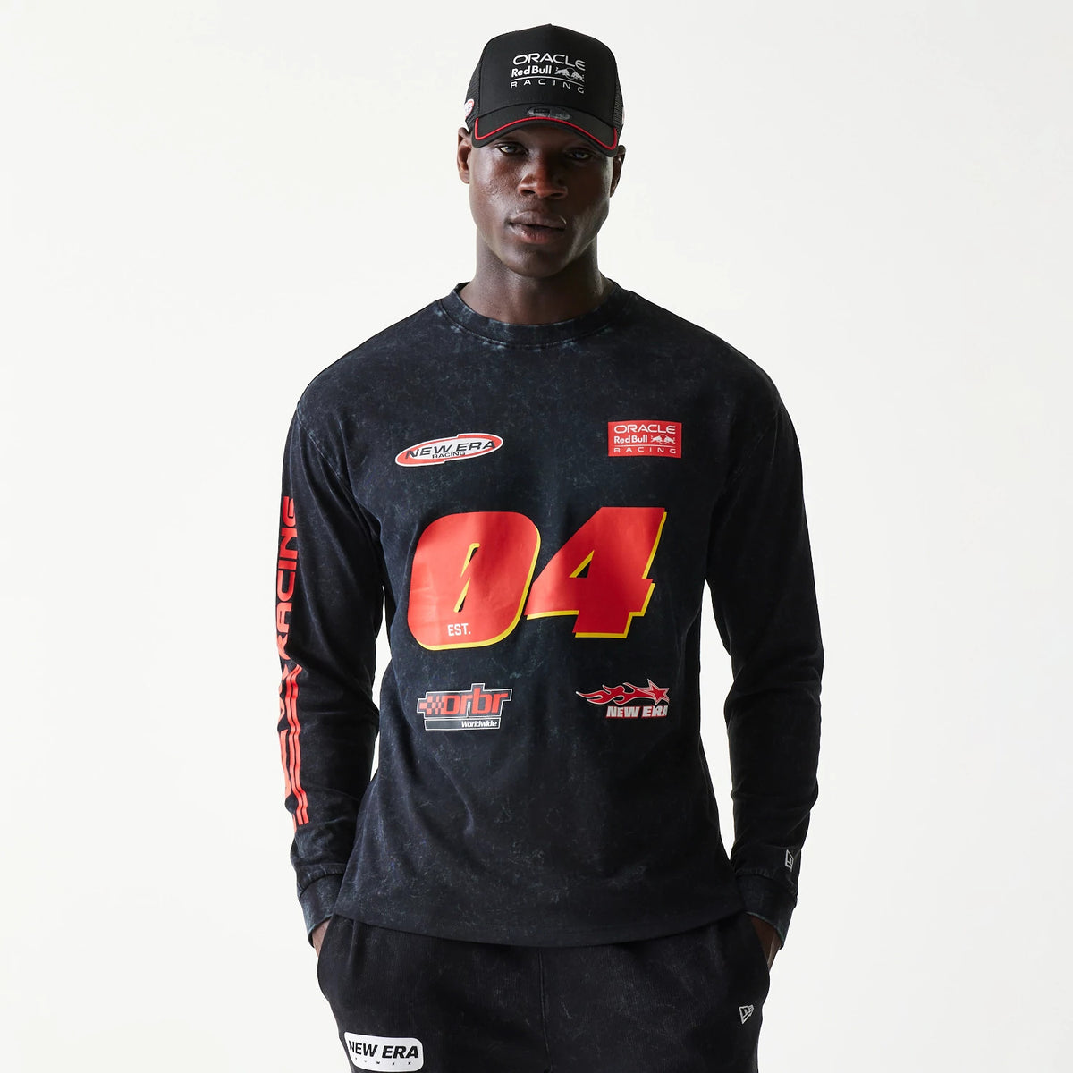 New Era Red Bull Racing Graphic Black Long Sleeve T-Shirt, front view on-model showing a red 04 graphic with multiple logos including a printed New Era logo on the chest, and vertical red Racing lettering on the left sleeve.