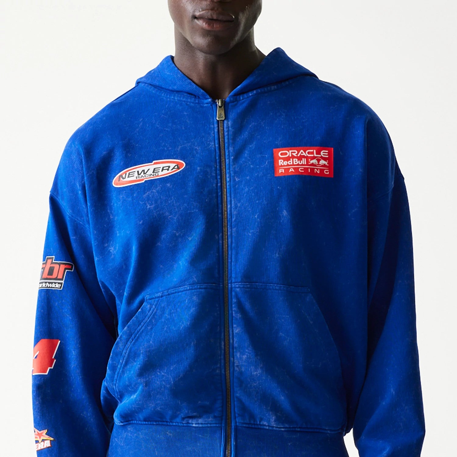 New Era Red Bull Racing Graphic Blue Dropped Shoulder Full Zip Hoodie, front view showing embroidered New Era and Oracle Red Bull Racing logos on the chest, with additional sponsor logos on the sleeve, worn by a model.