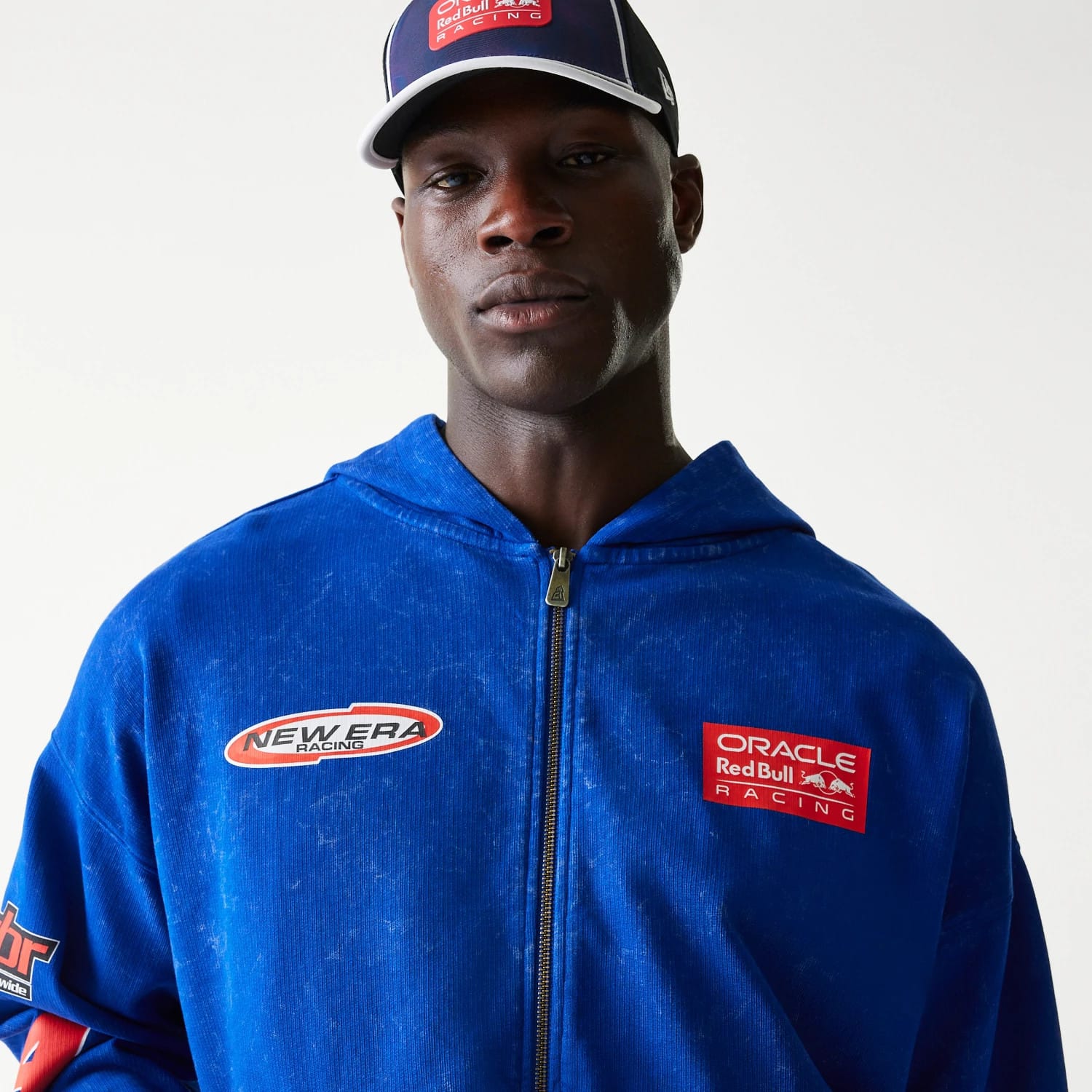 New Era Red Bull Racing Graphic Blue Dropped Shoulder Full Zip Hoodie, front view on-model displaying a blue colour with red embroidered Oracle Red Bull Racing logo on the right chest and a New Era Racing logo on the left chest.