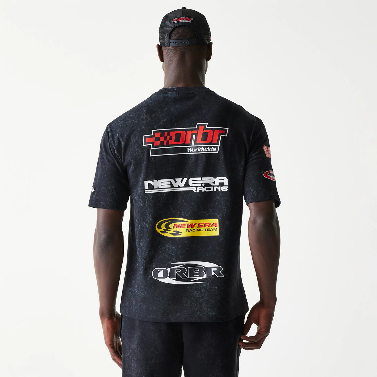 New Era Red Bull Racing Graphic Black Oversized T-Shirt, back view on a model showing multiple racing-themed graphics including a red and white DRBR logo, New Era Racing text, and a yellow New Era Racing Team logo near the bottom.