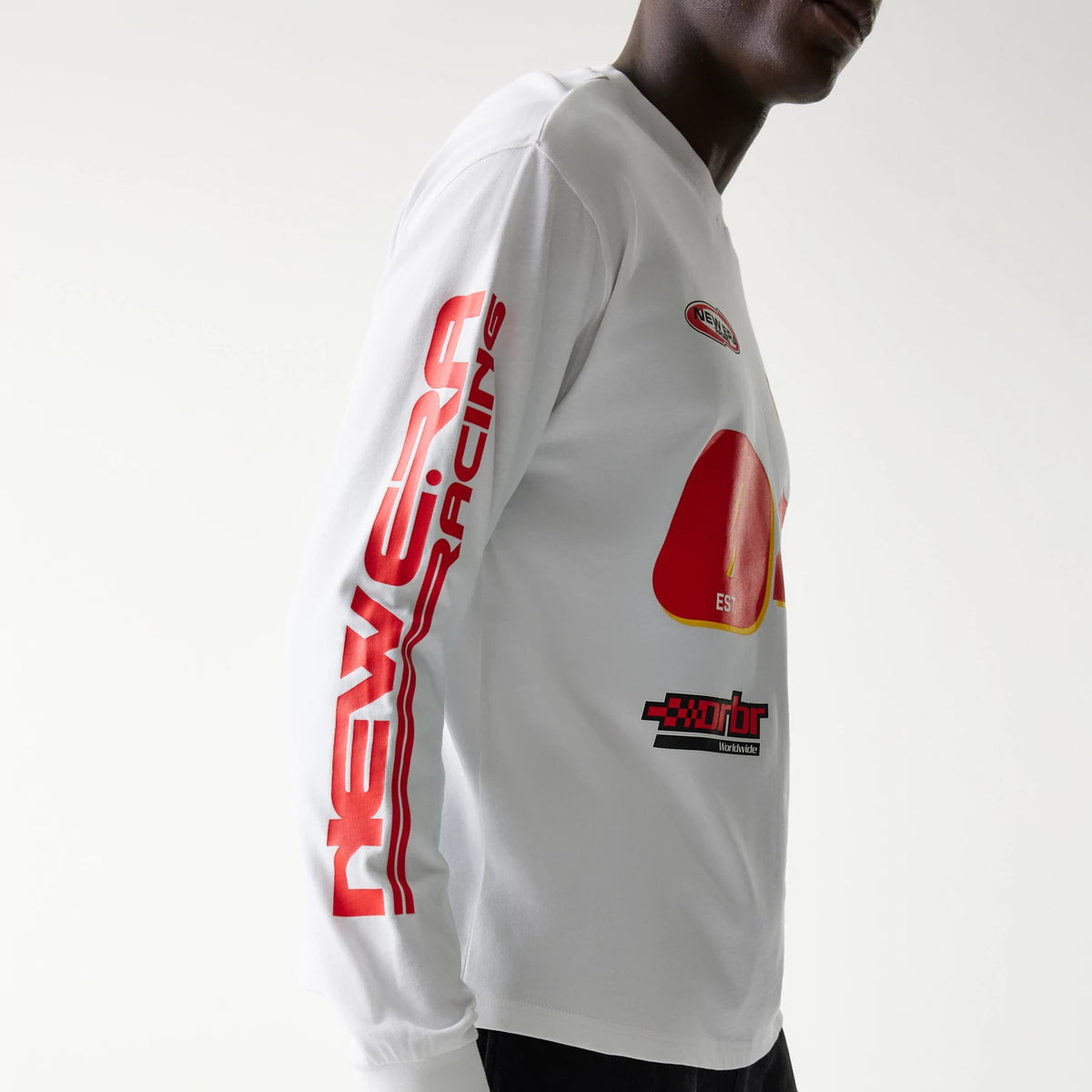New Era Red Bull Racing Graphic White Long Sleeve T-Shirt, side view on-model showing red New Era Racing text down the sleeve, a raised red graphic on the chest, and a small embroidered New Era logo near the shoulder.