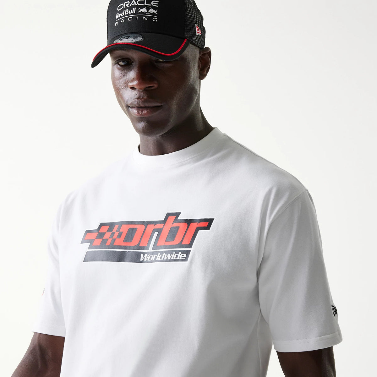 New Era Red Bull Racing Graphic White Oversized T-Shirt, front view on a model showing a large red and black orbr Worldwide graphic on the chest and a small embroidered New Era logo on the left sleeve near the hem.
