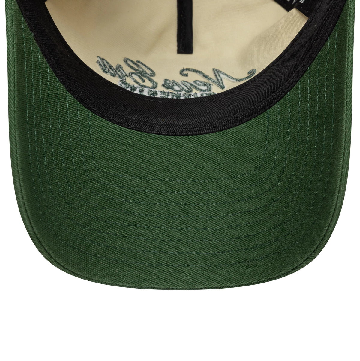 Womens New Era Cream 9TWENTY A-Frame Cap, inside view showing a green undervisor, black sweatband, and beige inner crown with intricate black script branding along the seam taping.