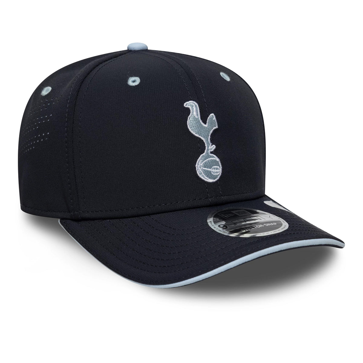Tottenham Hotspur FC Cockerel Navy New Era 9SEVENTY Stretch Snap Cap, three-quarter view showing the light blue embroidered cockerel logo on the front panel, a curved navy visor with a 9SEVENTY size sticker, and matching eyelets and top button.