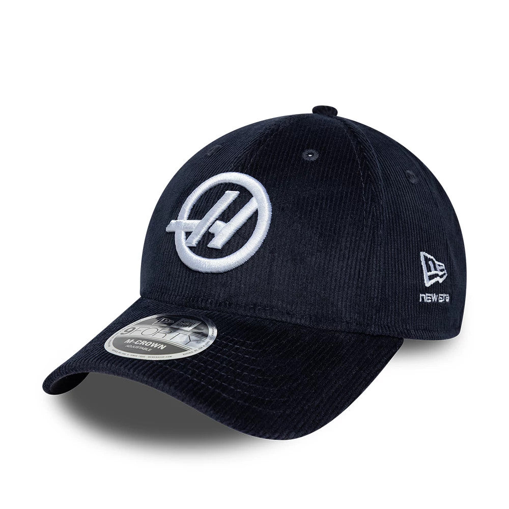 TGR Haas F1 Cord Navy New Era 9FORTY Cap, three-quarter view showing a white embroidered Haas logo on the front panel, a curved navy corduroy visor with a 9FORTY size sticker, and the New Era flag logo on the left side.