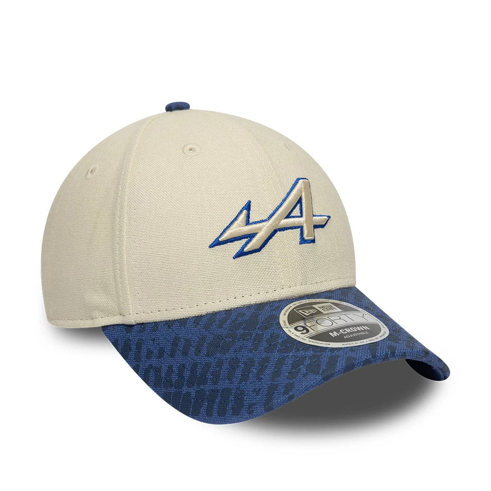 Alpine Racing Heritage Cream & Dark Blue New Era 9FORTY M-Crown Cap, three-quarter view showing the embroidered blue outlined A logo on the cream front panel, with a dark blue patterned visor and a 9FORTY size sticker.