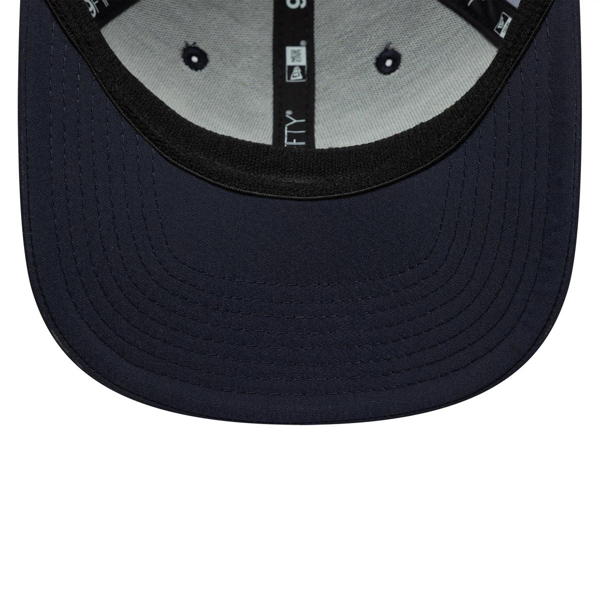 Alpine Racing All Over Print Navy New Era 9FIFTY Stretch Snap Cap, inside view showing a grey undervisor, black sweatband with New Era and 9FIFTY branding, and navy eyelets on light grey lining.