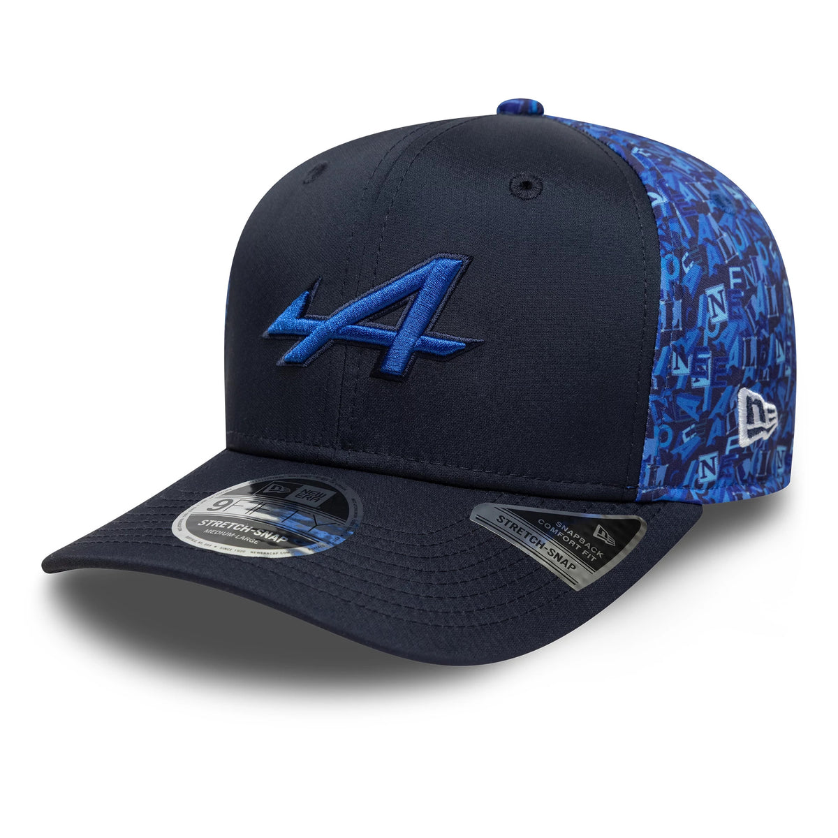 Alpine Racing All Over Print Navy New Era 9FIFTY Stretch Snap Cap, three-quarter view with the blue and black embroidered A logo on the structured navy front panel, featuring a blue patterned side and black visor with a 9FIFTY size sticker.