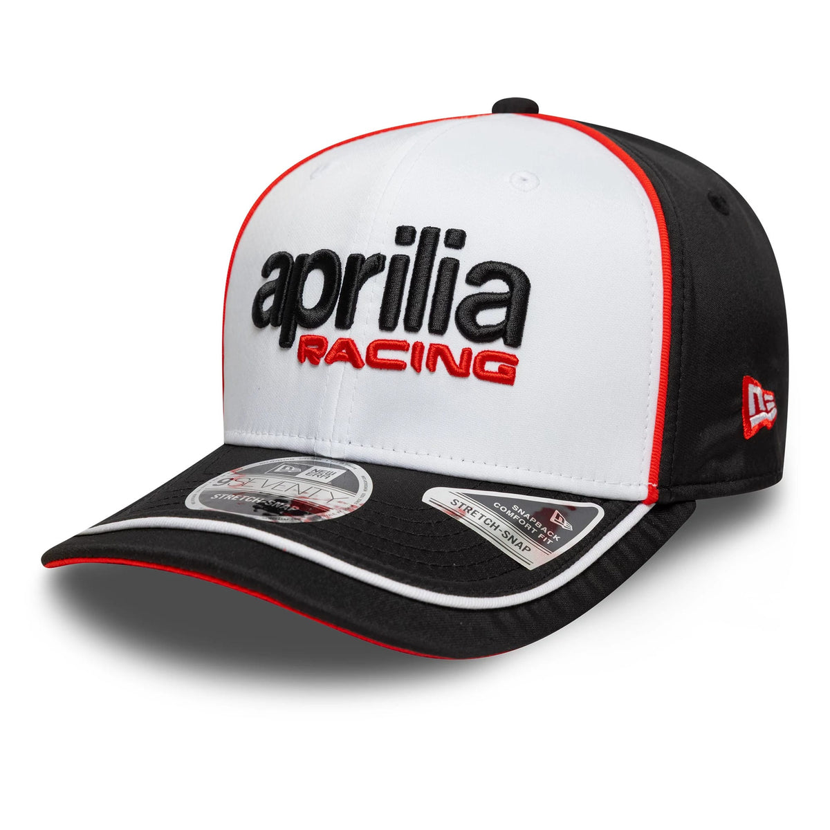 Aprilia Logo White New Era 9SEVENTY Stretch Snap Cap, three-quarter view showing raised black and red embroidered Aprilia Racing logo on the white front panel, with black visor featuring two size stickers, red trim and New Era flag on the left side.